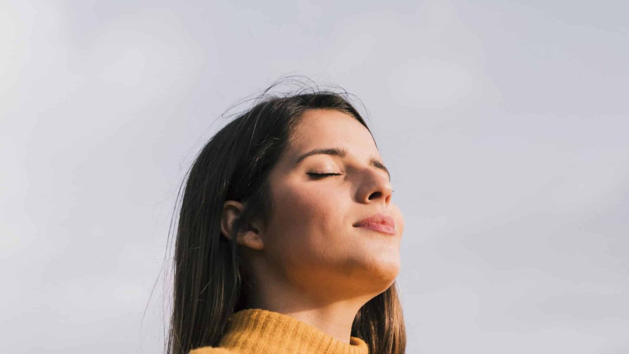 retrato de um mulher jovem com dela olhos fechados ficar contra ceu azul scaled 1e73d7f5