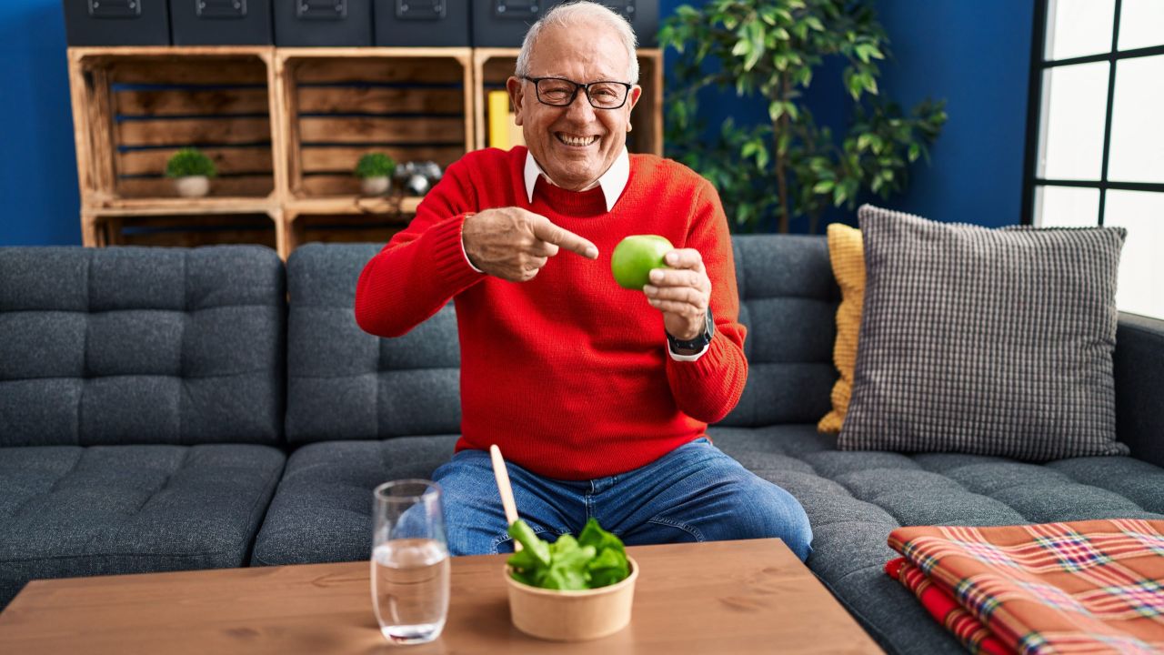 senior man with grey hair eating salad green apple smiling happy pointing with hand finger 1 scaled 69f98be9