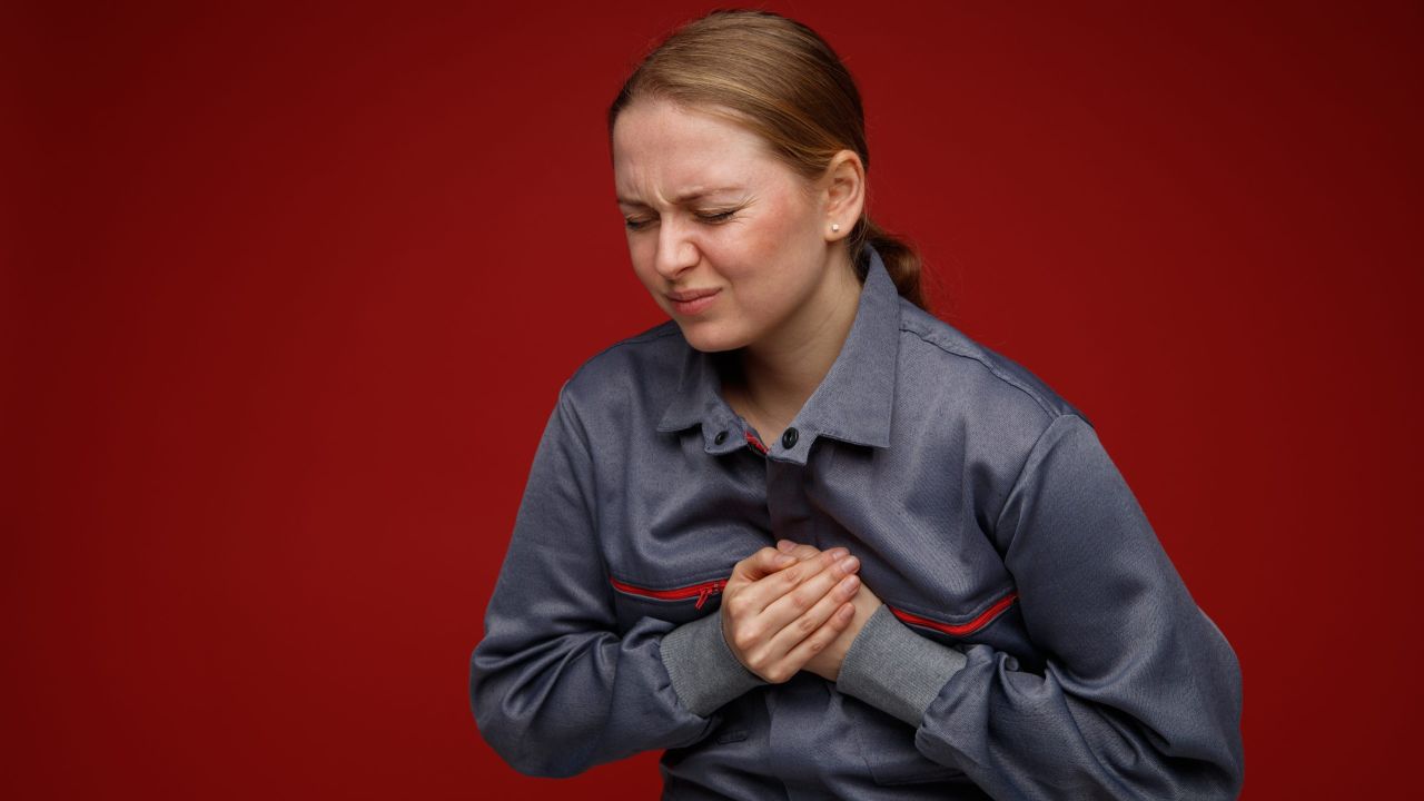 aching young blonde female engineer wearing uniform keeping hands chest with closed eyes scaled c13a193b