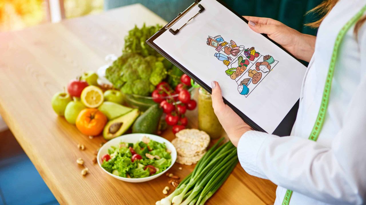 segurando o plano de refeicoes esquematicas para dieta com varios produtos saudaveis no fundo scaled e8ba89aa