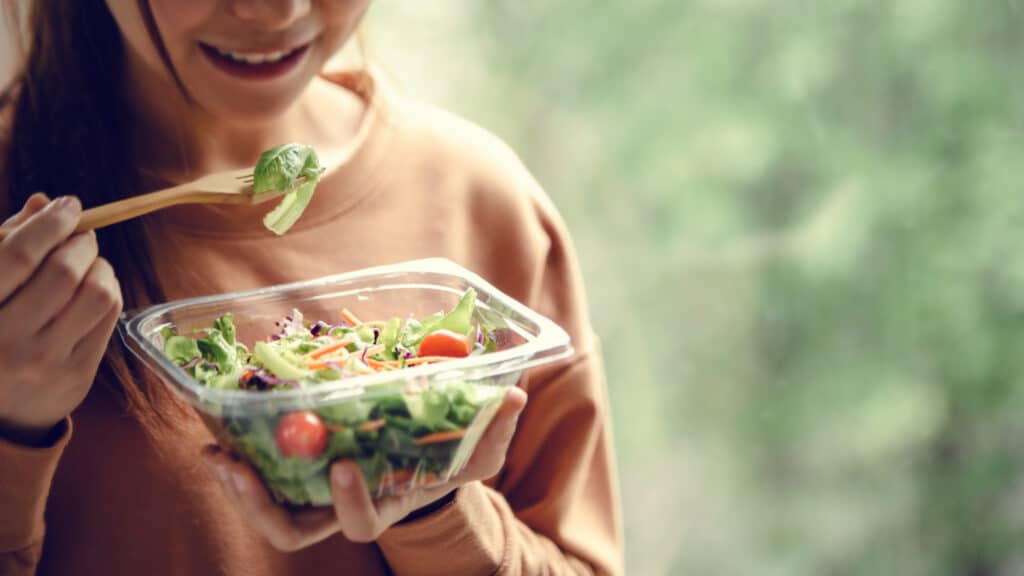 closeup woman eating healthy food salad focus salad fork