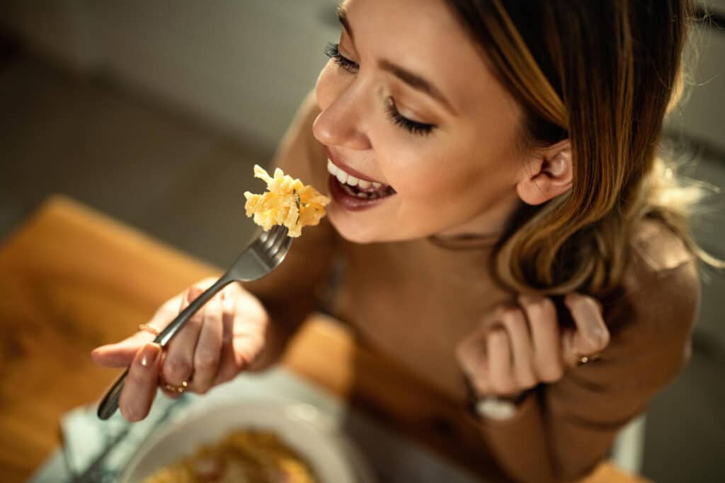 closeup young happy woman eating pasta dining table