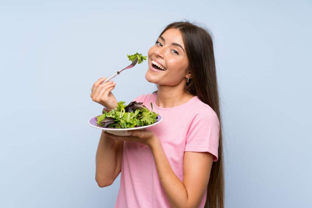 young woman with salad isolated blue background