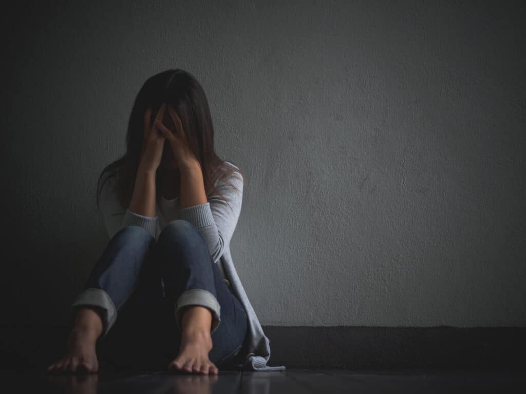 mulher triste abracar seu joelho e chorar sentado sozinho em um quarto vazio 1